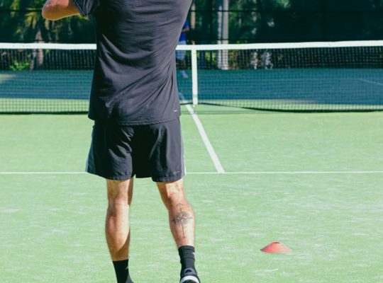 man in black t-shirt and shorts playing tennis